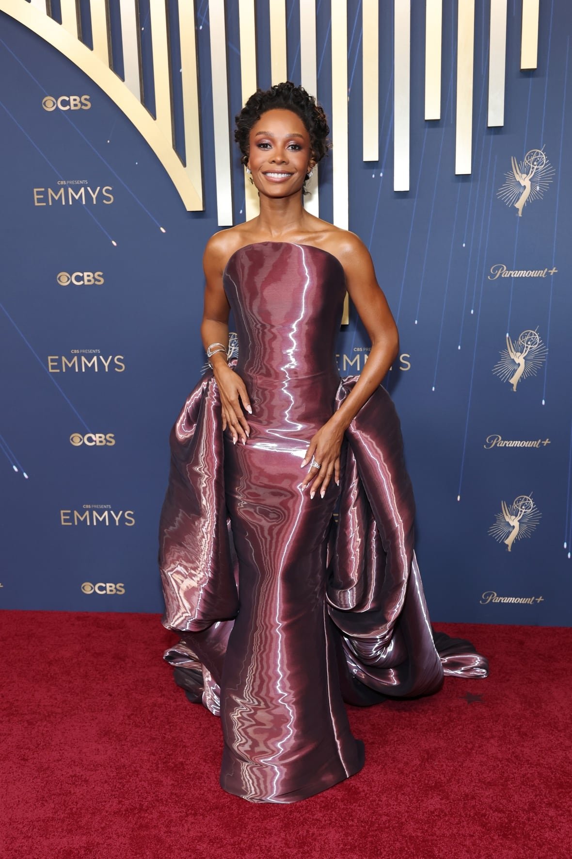A woman poses for a photo in a strapless gown. 