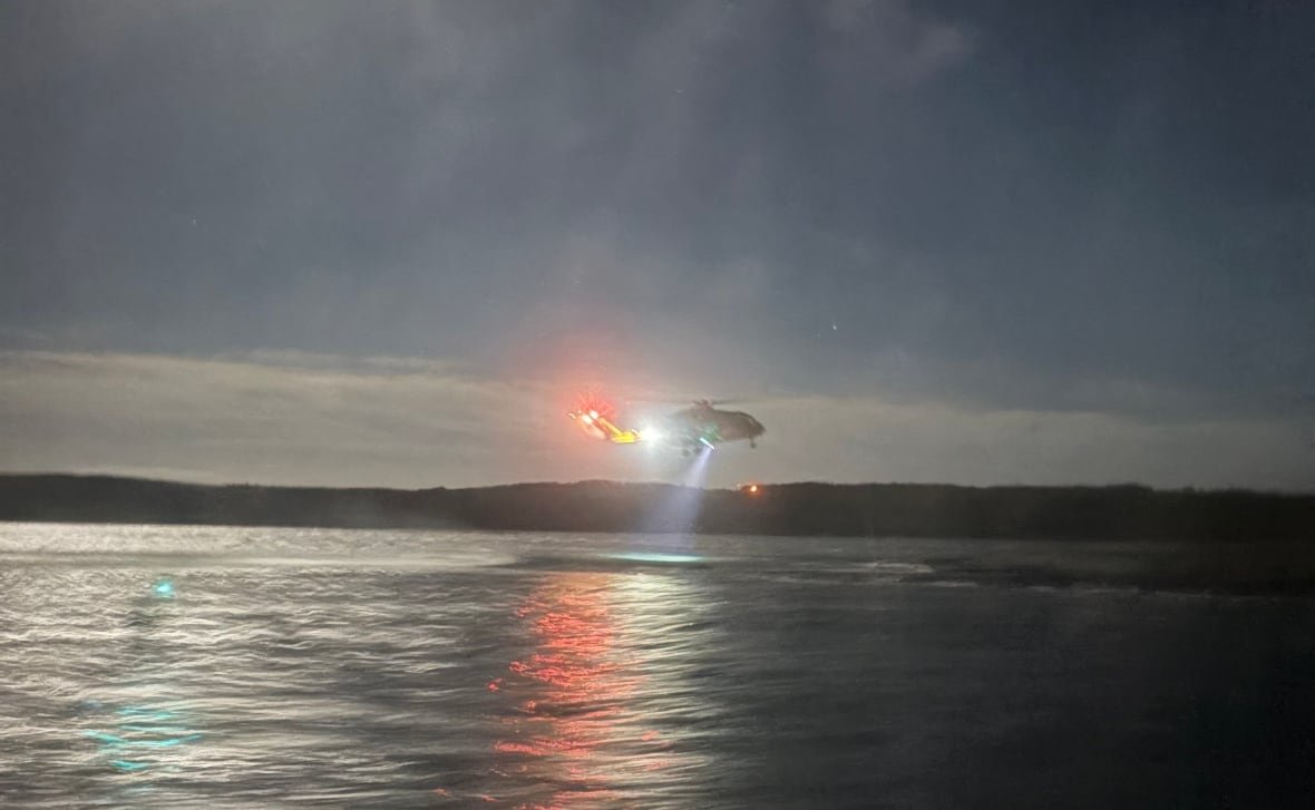A helicopter hovering above the ocean at night.