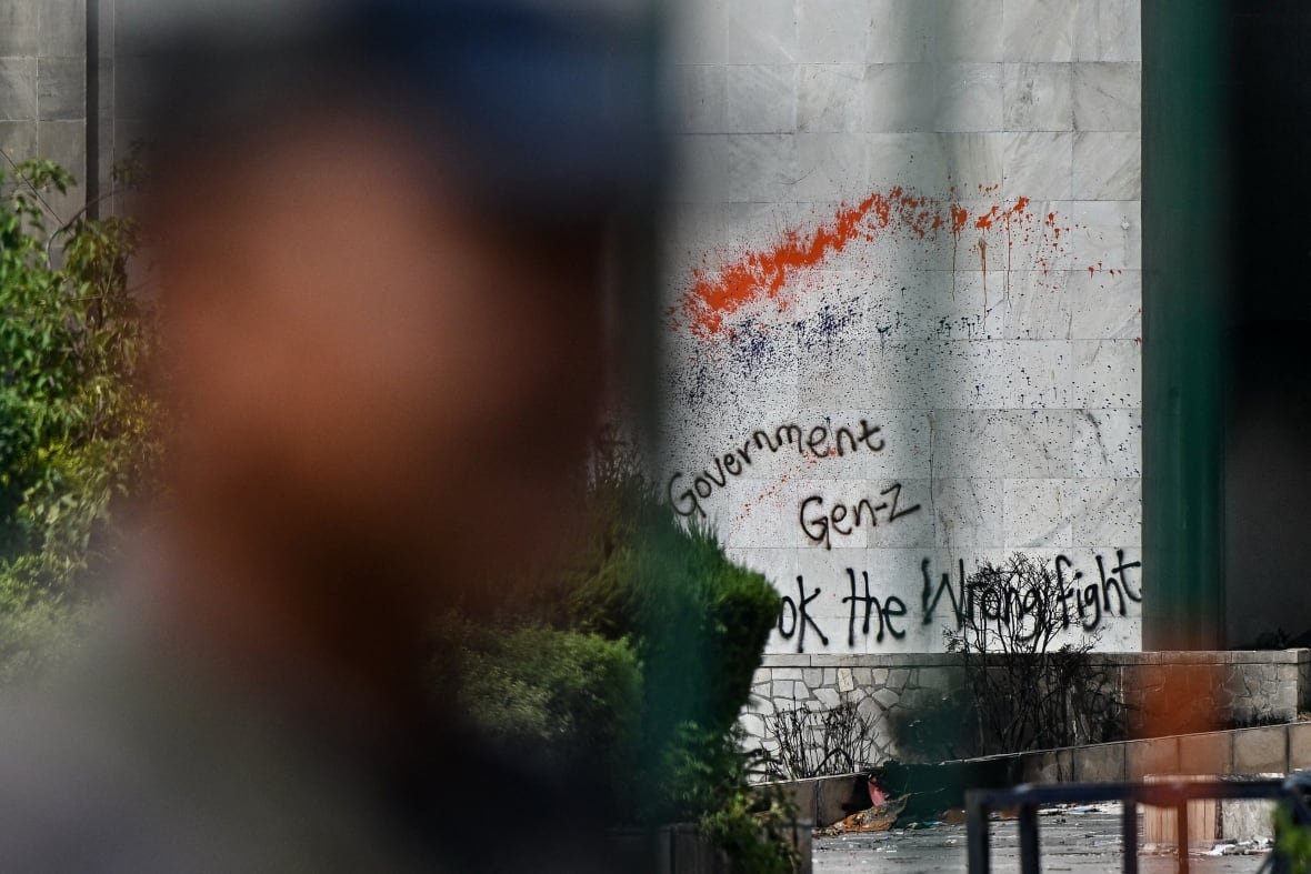 A blurred profile of a man is set against graffiti on a stone wall.