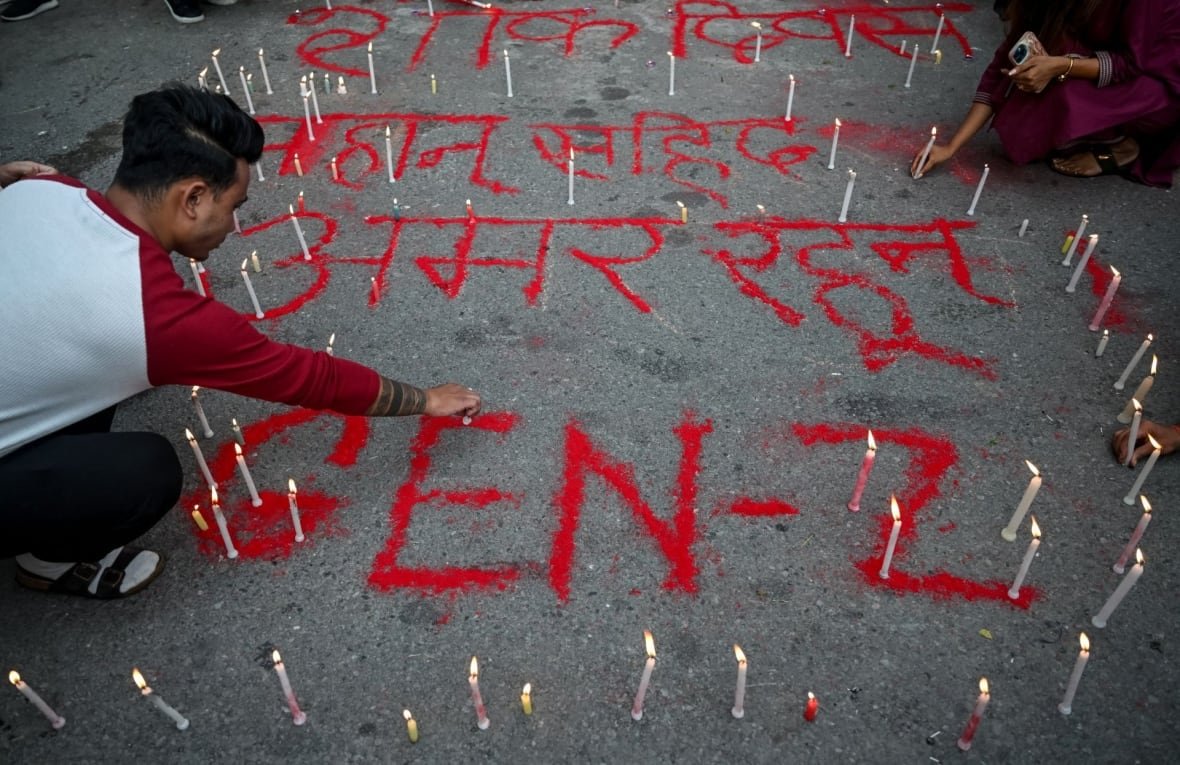A man touches the ground alongside graffiti, with the words Gen Z, surrounded by candles.