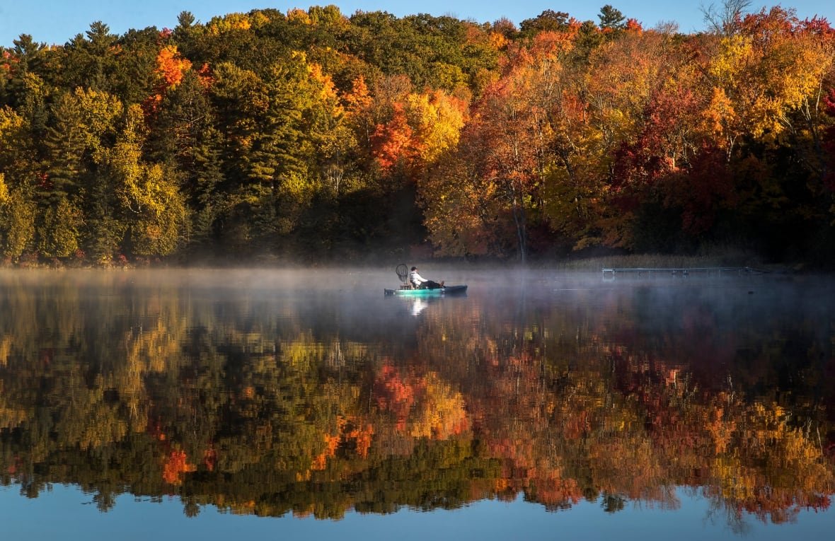 An especially warm fall in Ontario means the province may not get the colourful array of fall foliage that usually transforms treetops this time of year. A fisherman in a kayak on Bass Lake is framed by fall colours in central Ontario, Monday, October 10, 2022. 