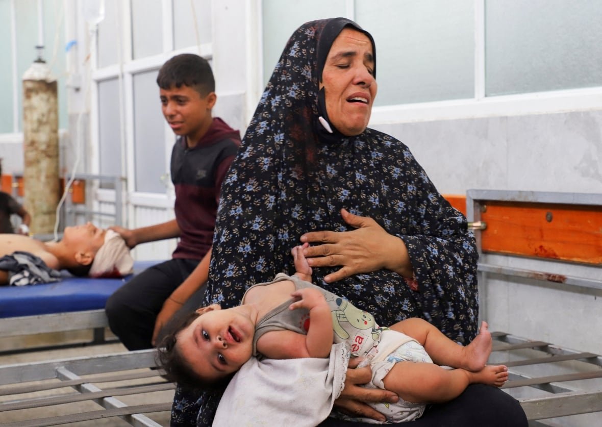 A crying woman holds a limp child. 