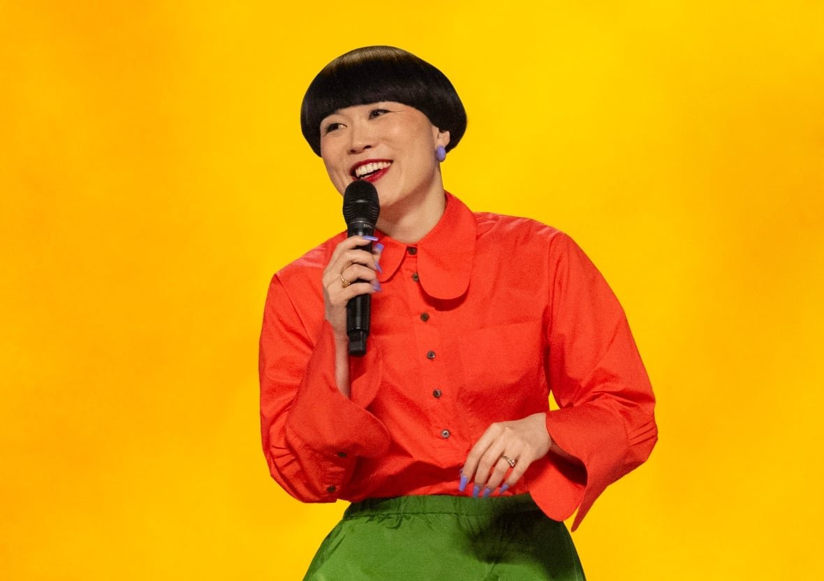 A smiling woman speaks into a microphone.