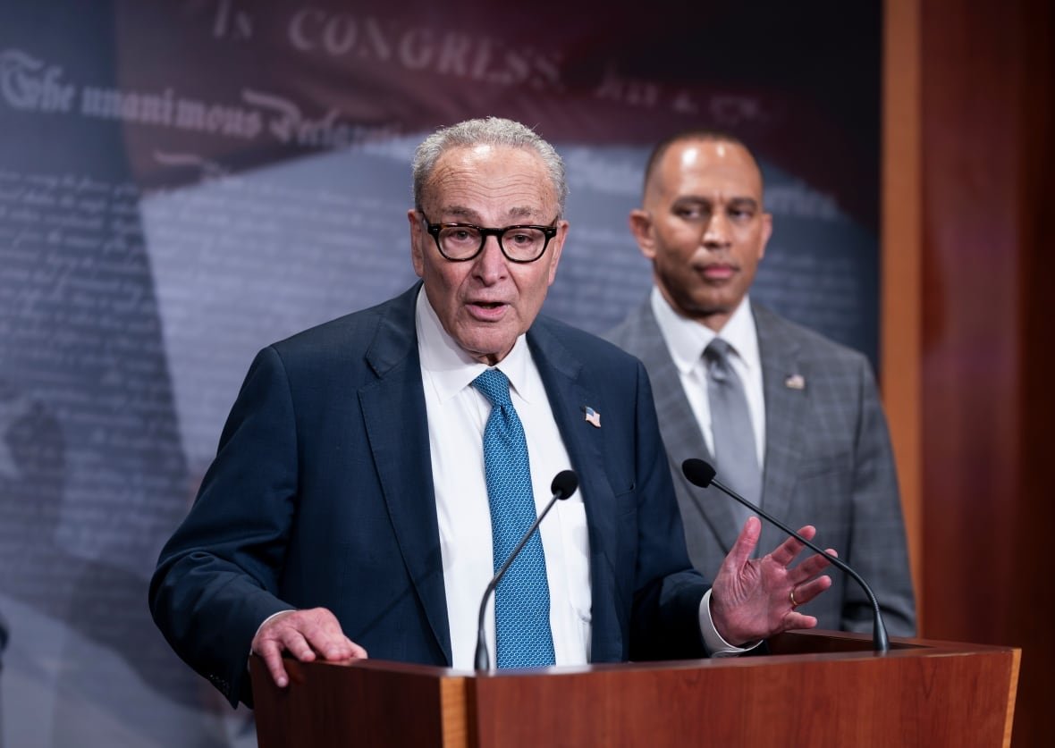 Two men in suits speak at a podium