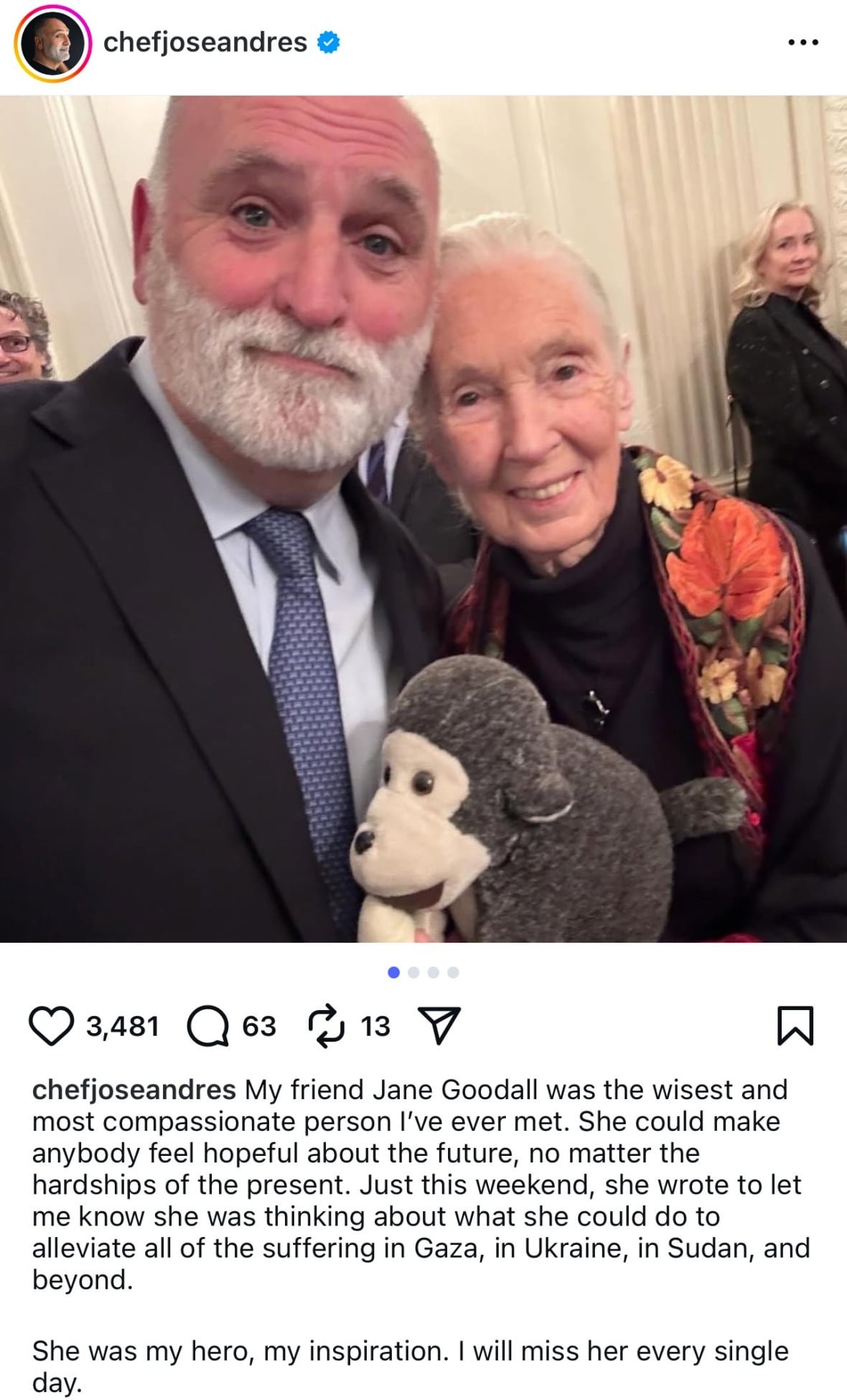 A social media post with an image of a bald man with a grey beard, wearing a dark suit, standing with his arm around a woman who has her grey hair pulled back and is wearing a flower-print scarf over a black top and holding a stuffed monkey toy in her hands.