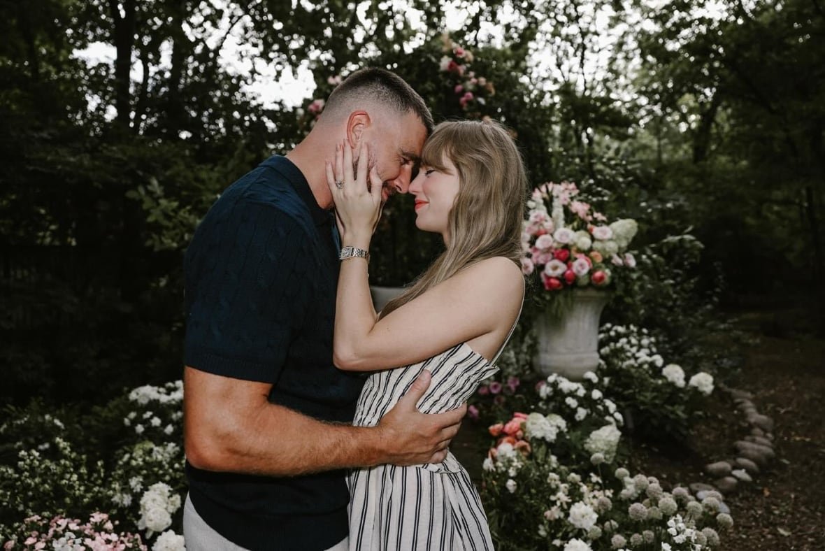 A man and a woman embrace in a flower filled garden