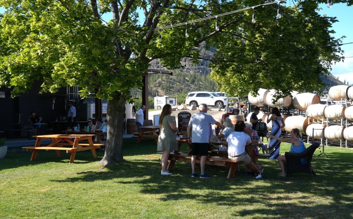 People sit at a an outdoor table at a the Lightning Rock winery in Summerland.