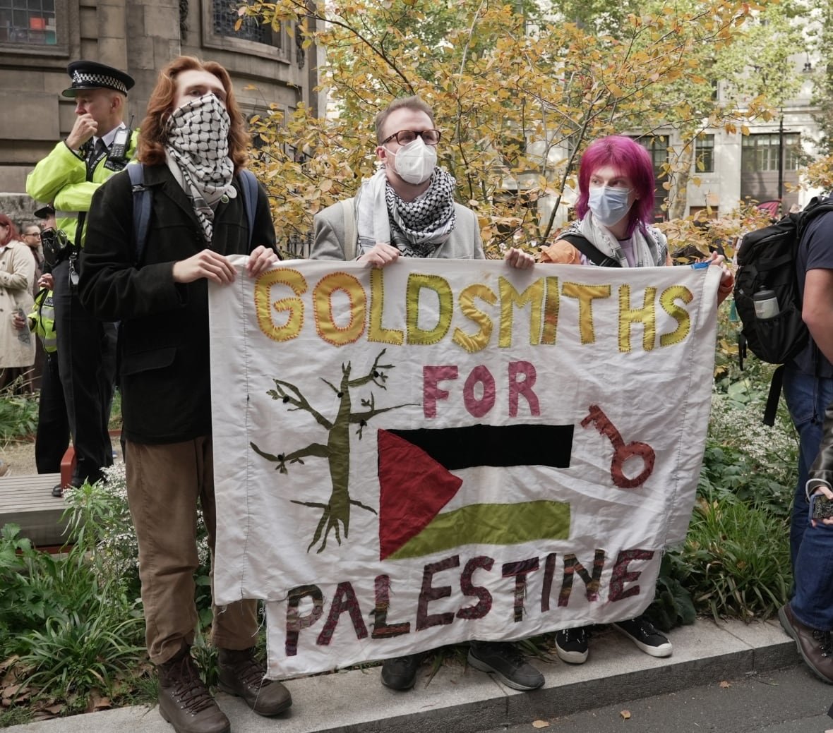 People stand at the back of a crowd in front of King's College London on Tuesday ahead of a student led March, protesting Israel's war in Gaza. 
