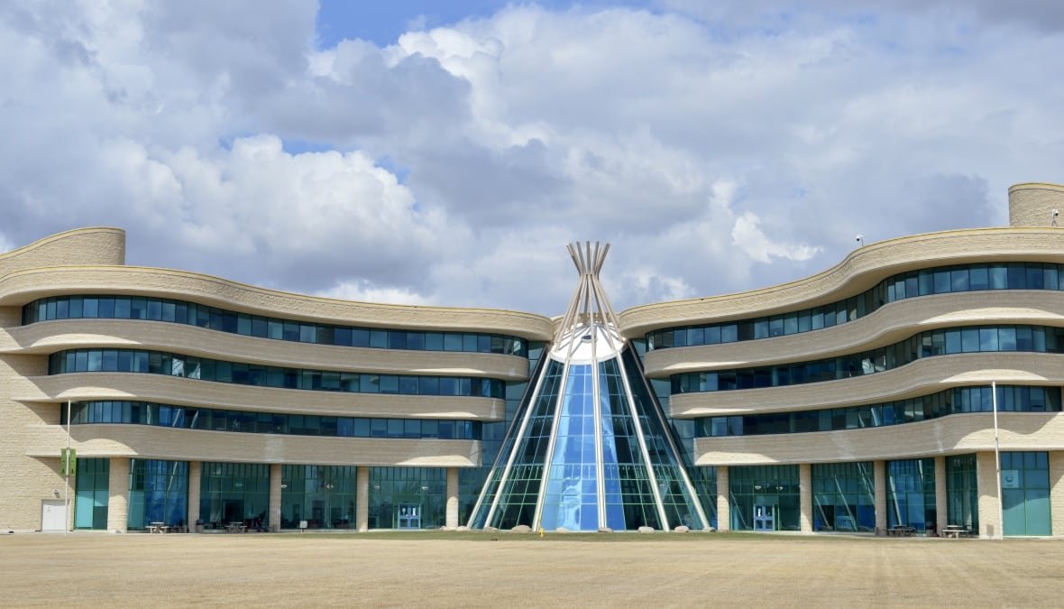 A sandstone building with flowing lines and a blue glass entryway in the shape of a teepee.