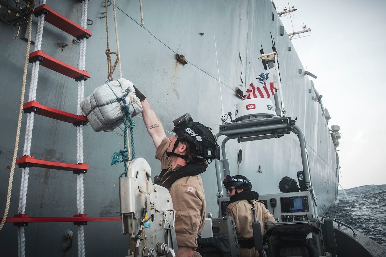 A man handing a square package up a rope.