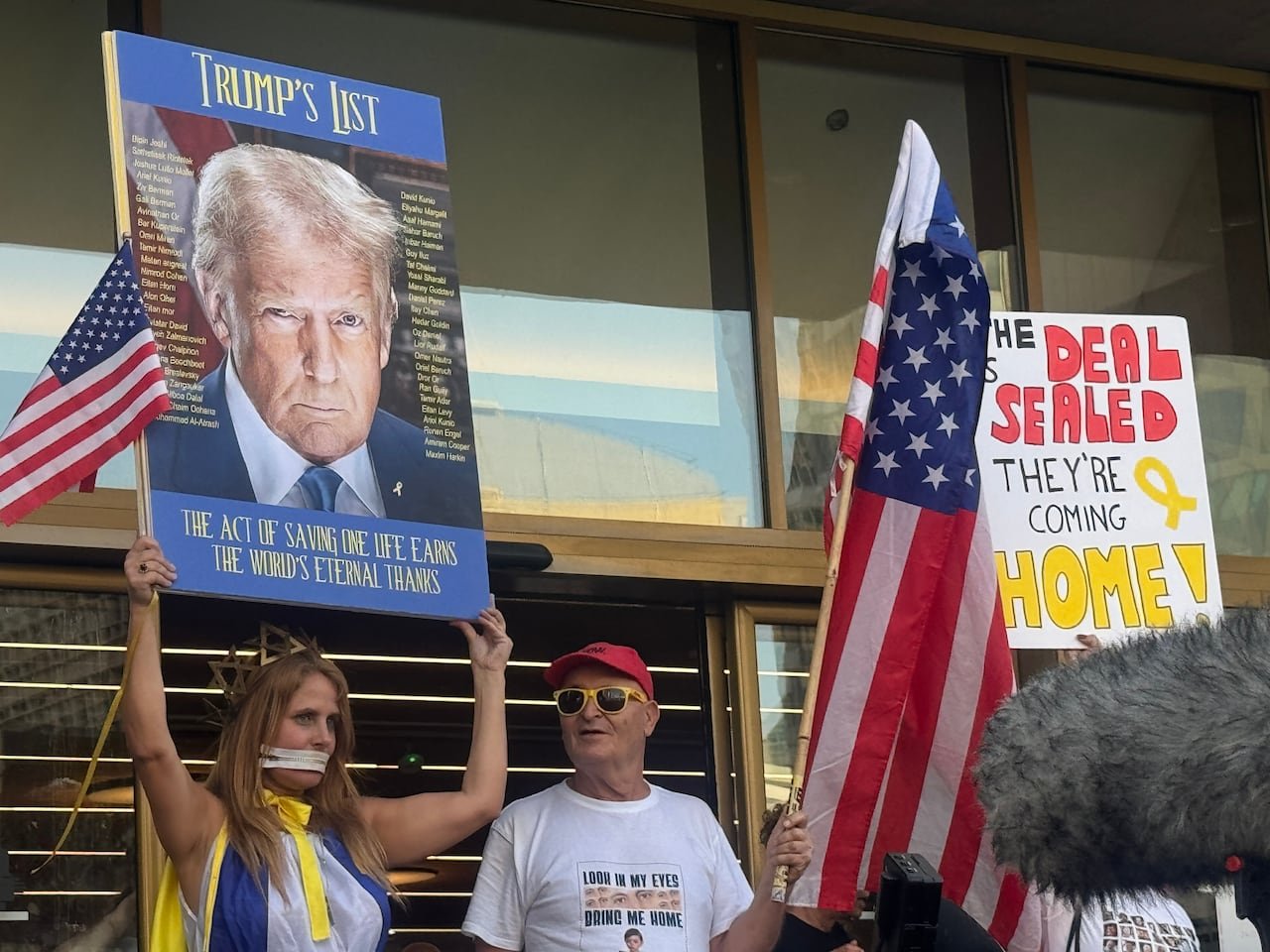 Demonstrators hold up signs and flags.