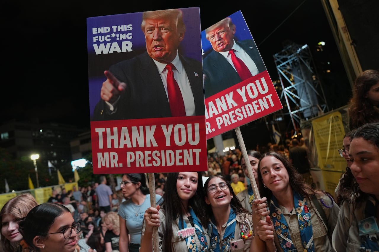 Demonstrators hold up signs depicting a person and the words, 'Thank you Mr. President.'