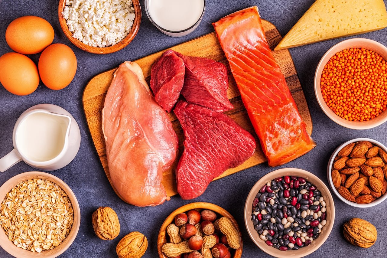 Protein-rich foods like meat, nuts, cheeses and eggs on a table and board.