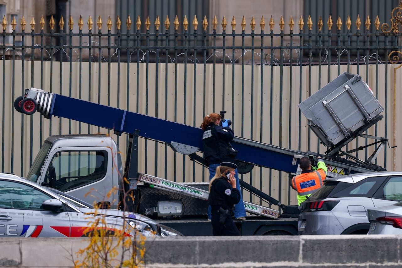 A police officer takes a photo of a crane believed to have been used in a robbery at the Louvre Museum.