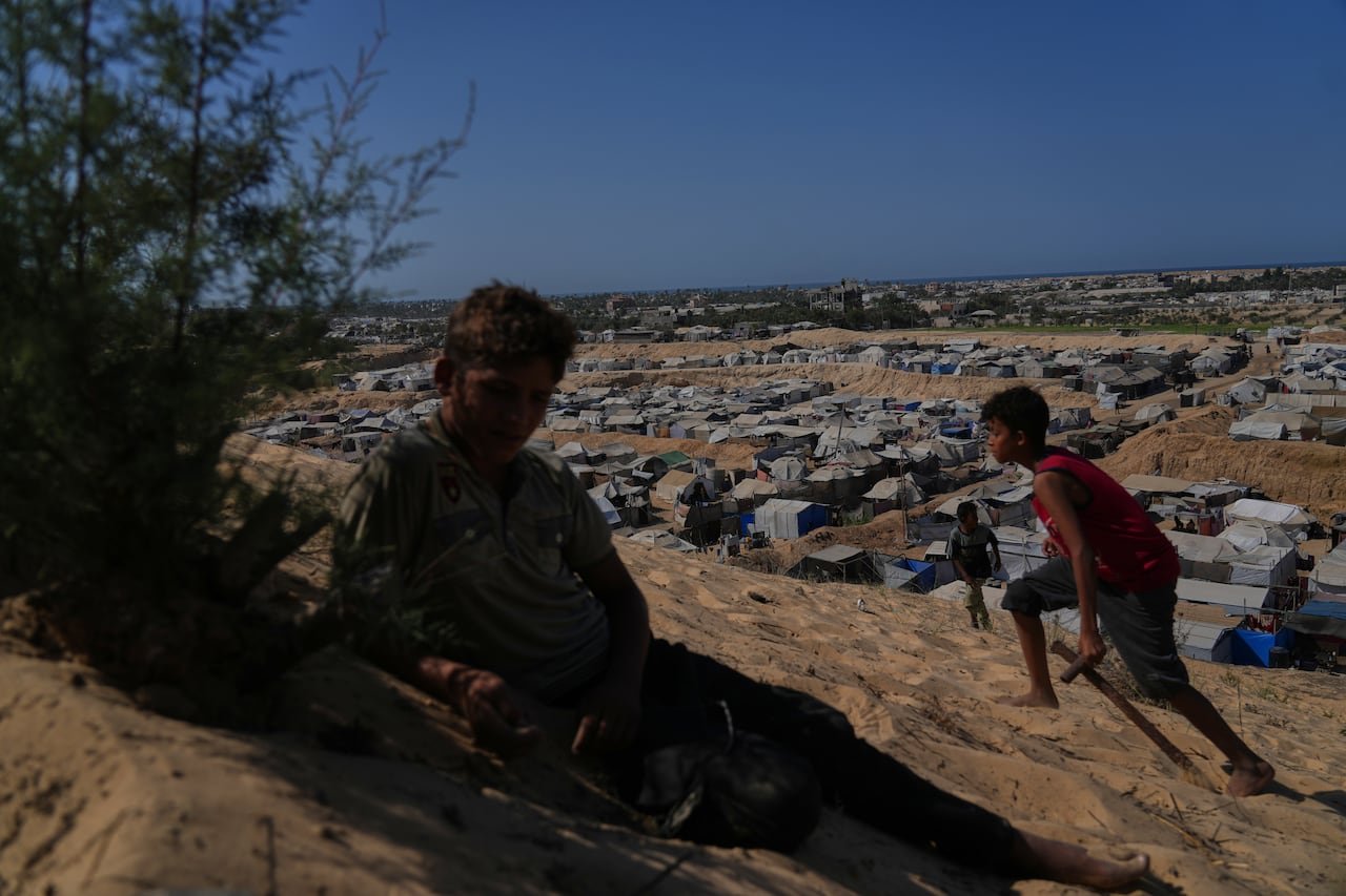 Two children on a hill overlooking tents