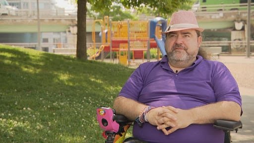A person sits in a park, looking at the camera.