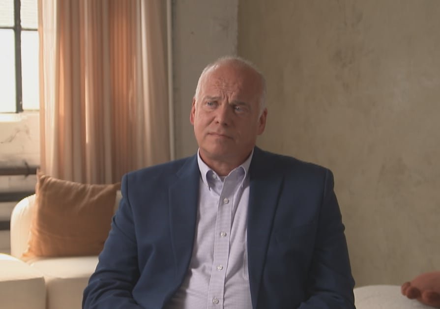 A man in a suit sitting down in a modern living room