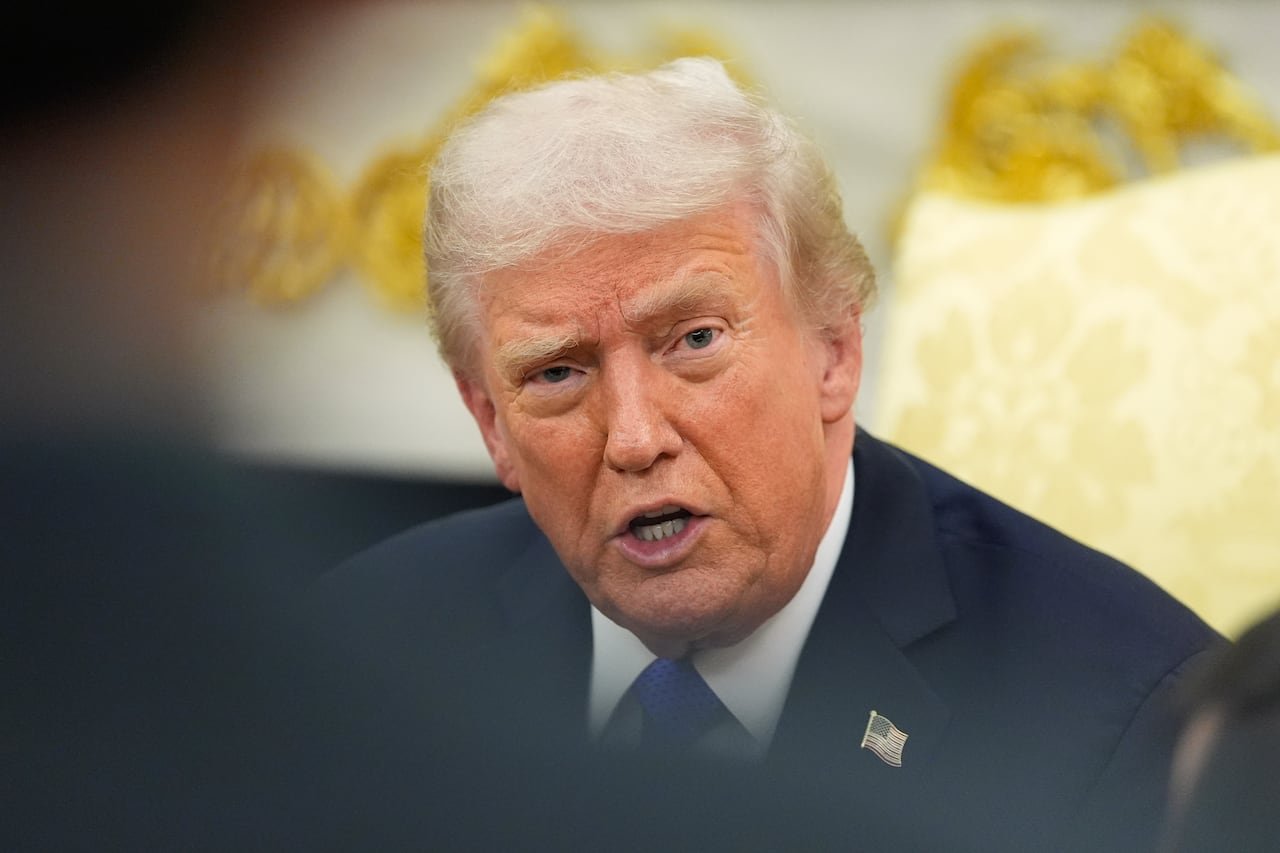 A man with thin white hair speaks into the camera