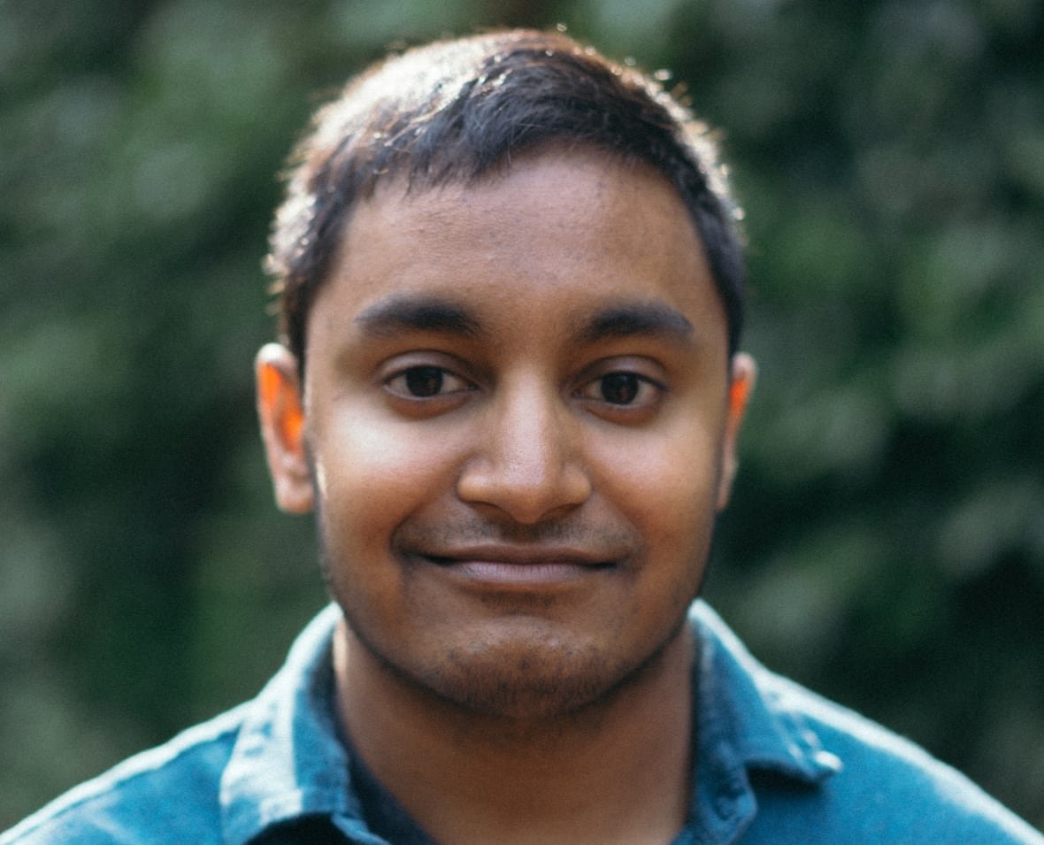 Portrait of a man in a blue shirt standing outside
