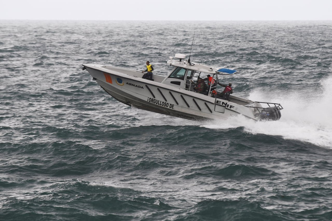 A speedboat contains several people as it rides on a wave in a body of water.
