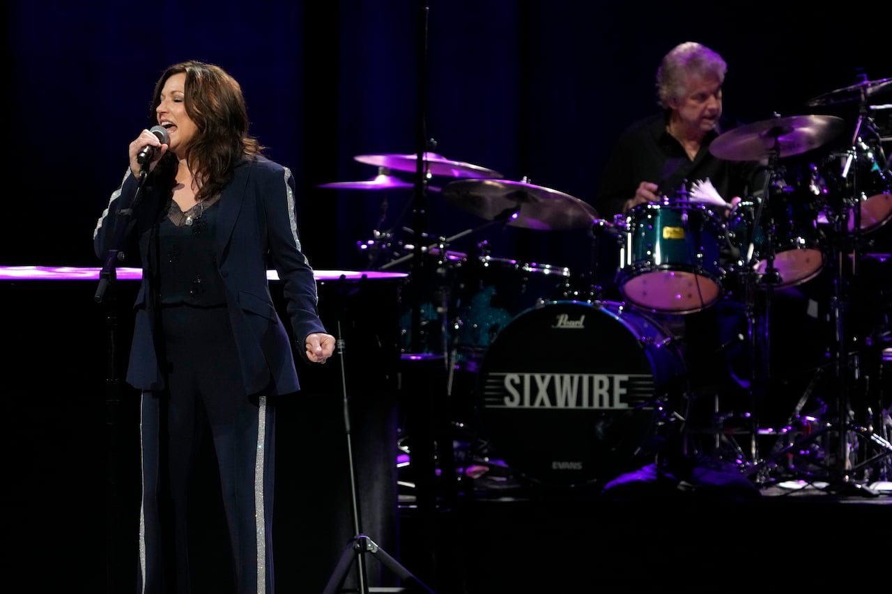 A woman sings into a microphone on a stage.