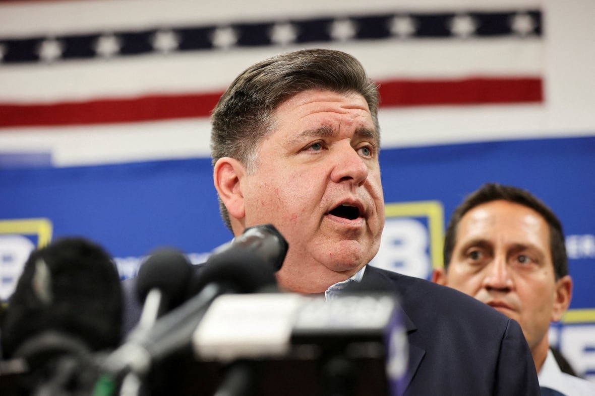 A man wearing a dark suit speaks at a podium